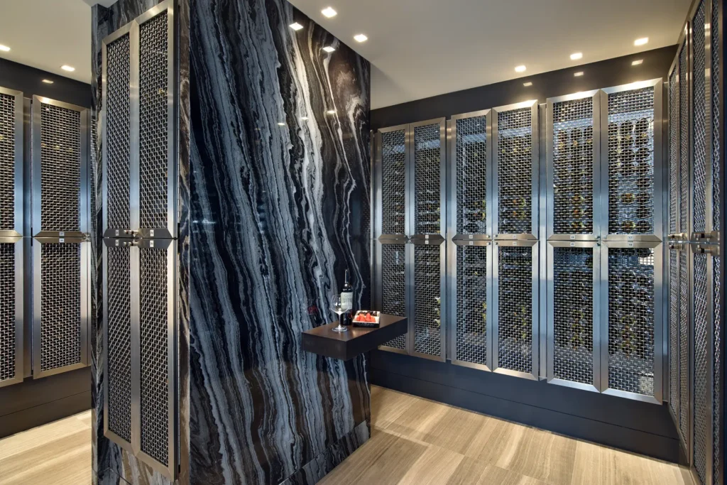A large veined marble wall stands beside metal mesh wine racks in the Regalia Wine Room