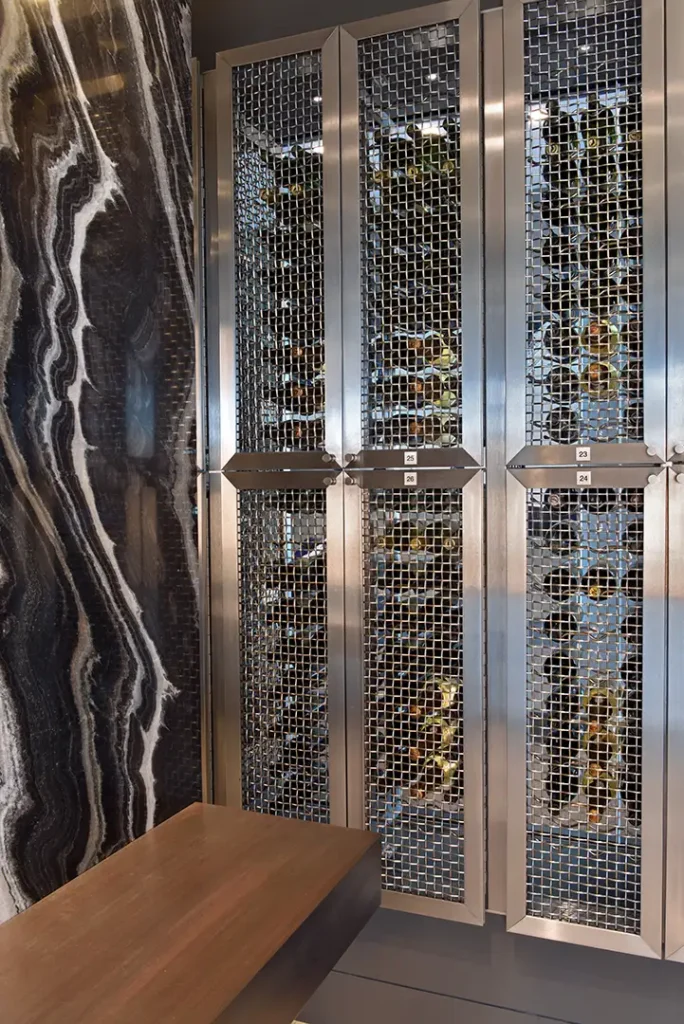 Silver-framed metal mesh wine racks stand beside a black and white veined stone wall in the Regalia Wine Room