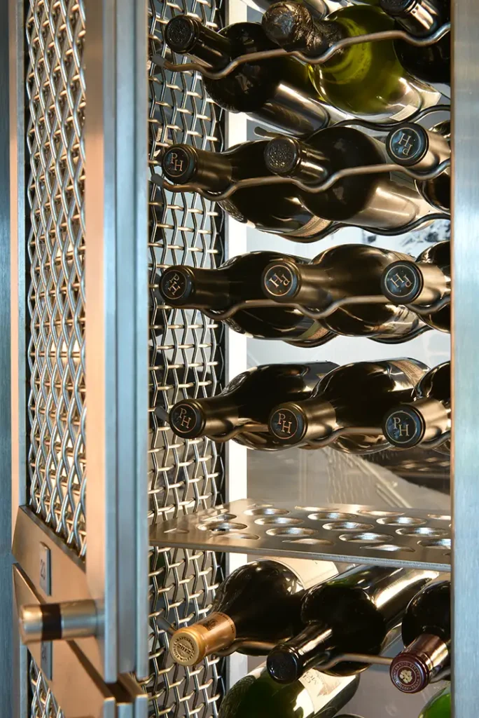 Wine bottles are arranged on metallic racks against a lattice-patterned background in the Regalia Wine Room