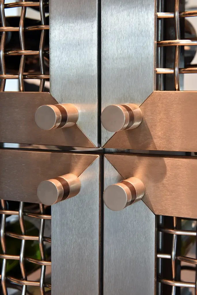 Brushed metal panels with cylindrical knobs and a wire mesh background are part of the Regalia Wine Room