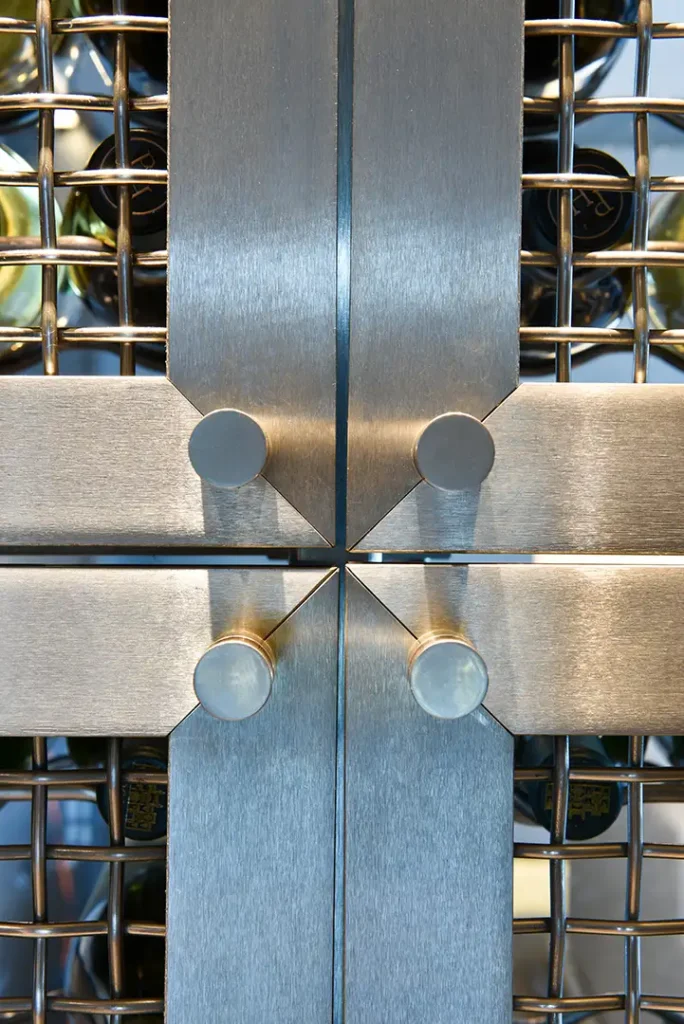 Brushed stainless steel bars and circular metal knobs surround bottles in the Regalia Wine Room
