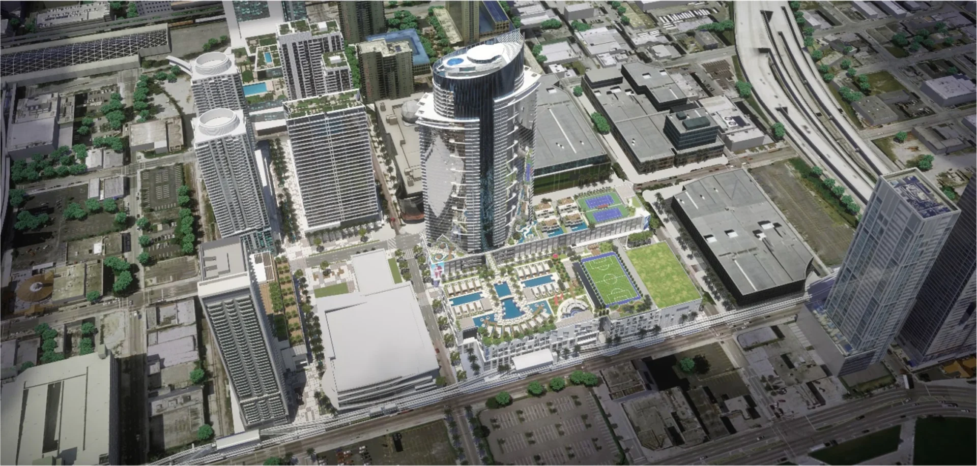 A central skyscraper at Paramount Miami Worldcenter is surrounded by various urban buildings, streets, and outdoor sports courts