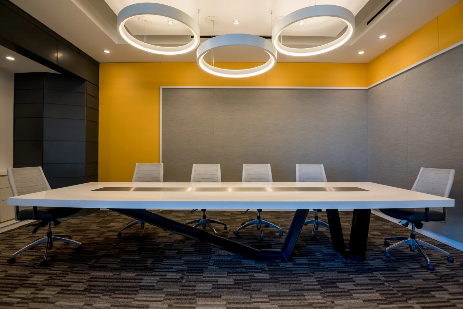 Three large circular light fixtures hang over a white conference table in the ODP Architecture & Design Headquarters meeting room