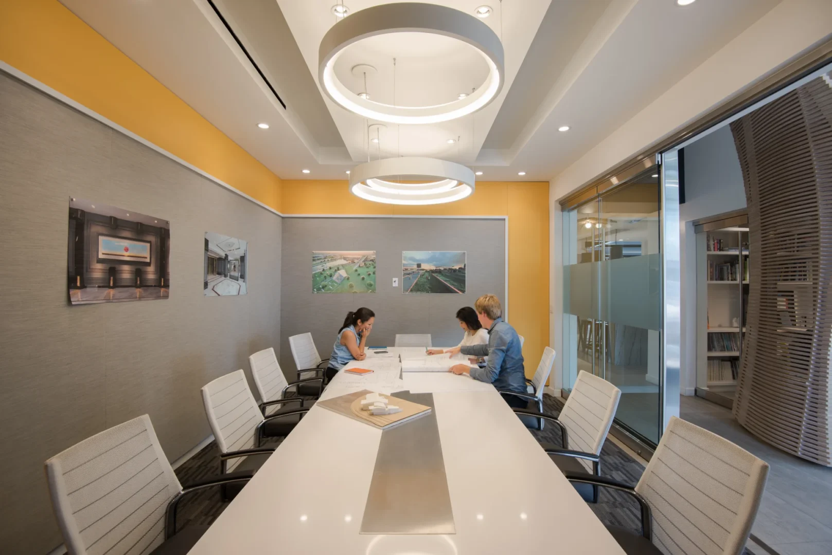 A large white conference table and three people are in an ODP Architecture & Design Headquarters meeting room