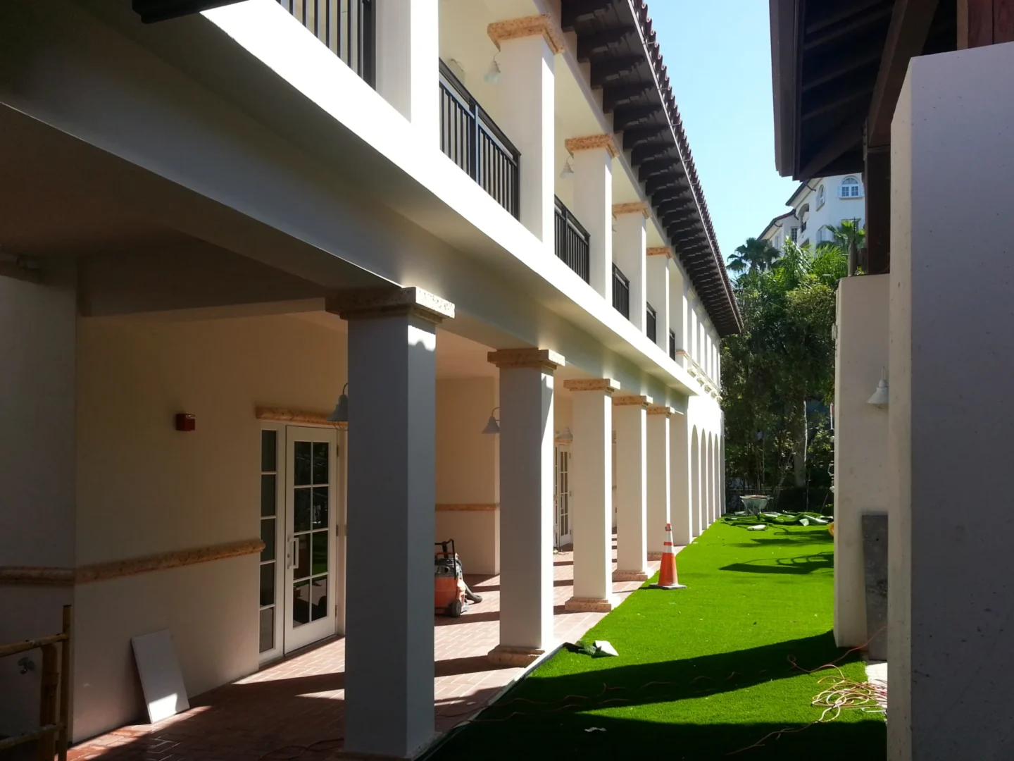 White columns at Fisher Island Day School border a green artificial turf area with an orange traffic cone