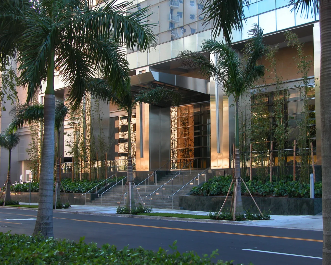 Palm trees frame the glass and metal entrance of the Naples Beach Four Seasons Resort & Residences