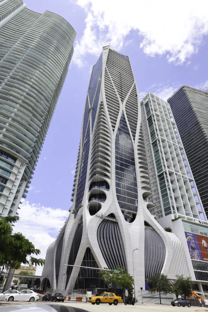 One Thousand Museum stands among other skyscrapers above a street with a yellow taxi and cars