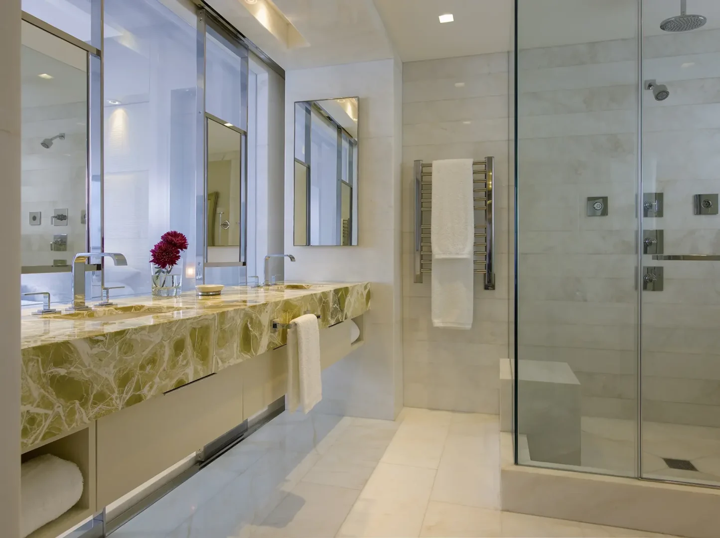 A marble-topped vanity and a glass shower enclosure are in the Penthouse 1 bathroom