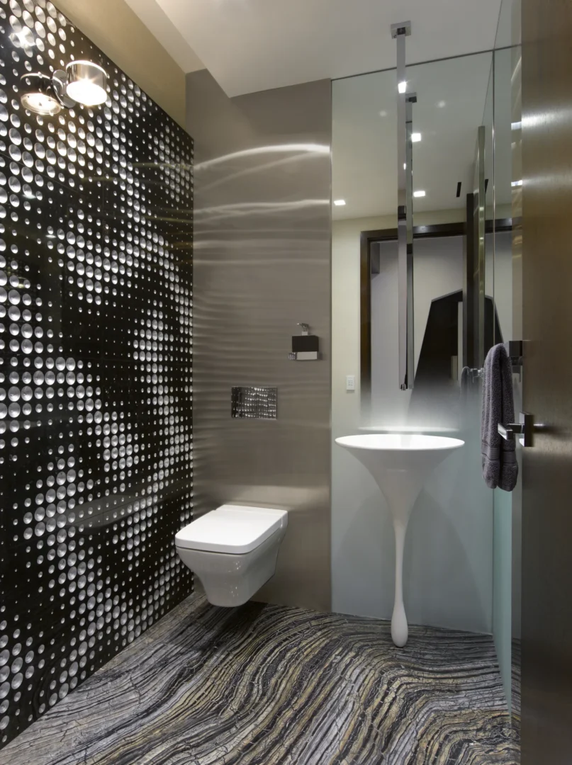 En el cuarto de baño del ático 2, una pared con un estampado en blanco y negro se encuentra junto a un inodoro blanco y un lavabo con pedestal.