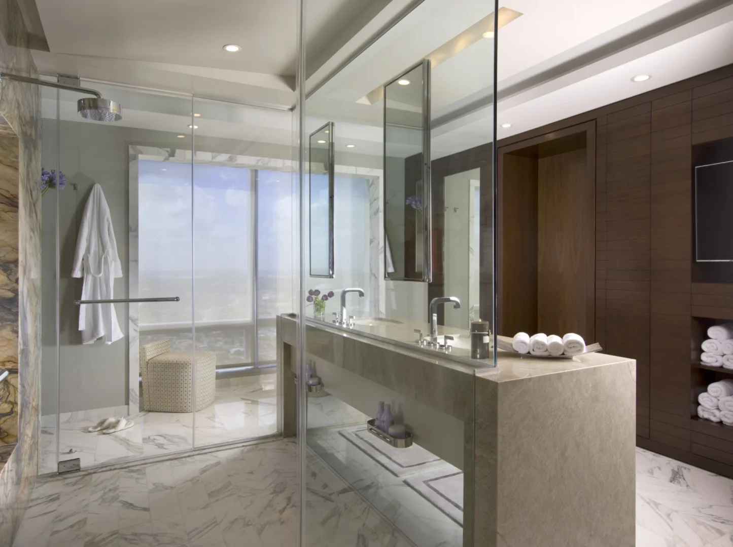 Este ático de tres baños cuenta con un lavabo doble de mármol y una mampara de ducha de cristal.