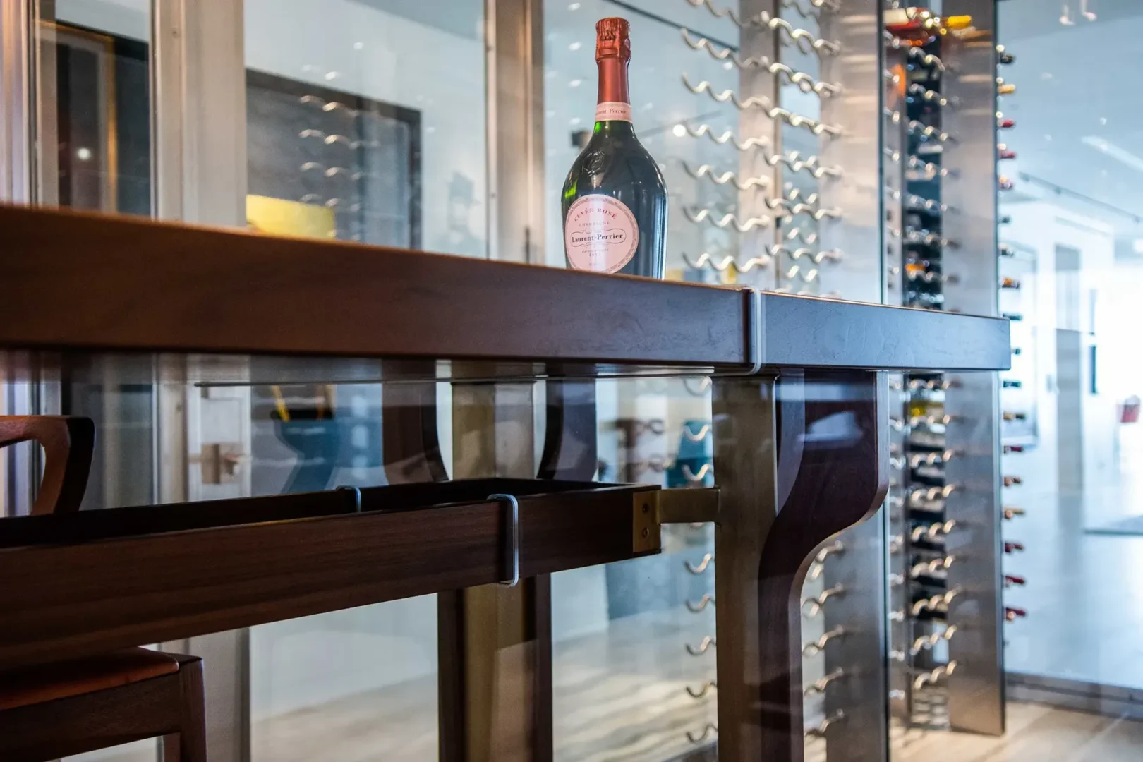 A champagne bottle sits on a dark wooden counter near a metal wine rack in Surfside Seaway
