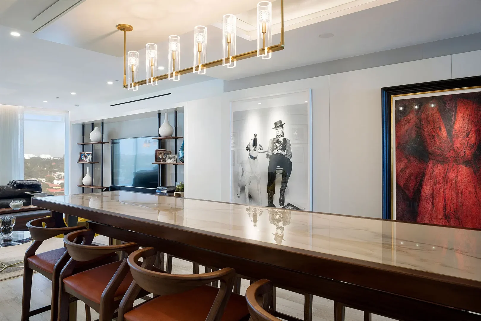 A long marble-topped table and modern gold chandelier are featured in the Surfside Seaway dining area