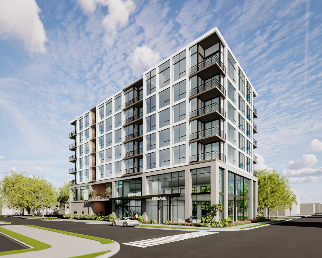 A multi-story building with large windows and balconies at The Avery borders a street with a white car and green trees
