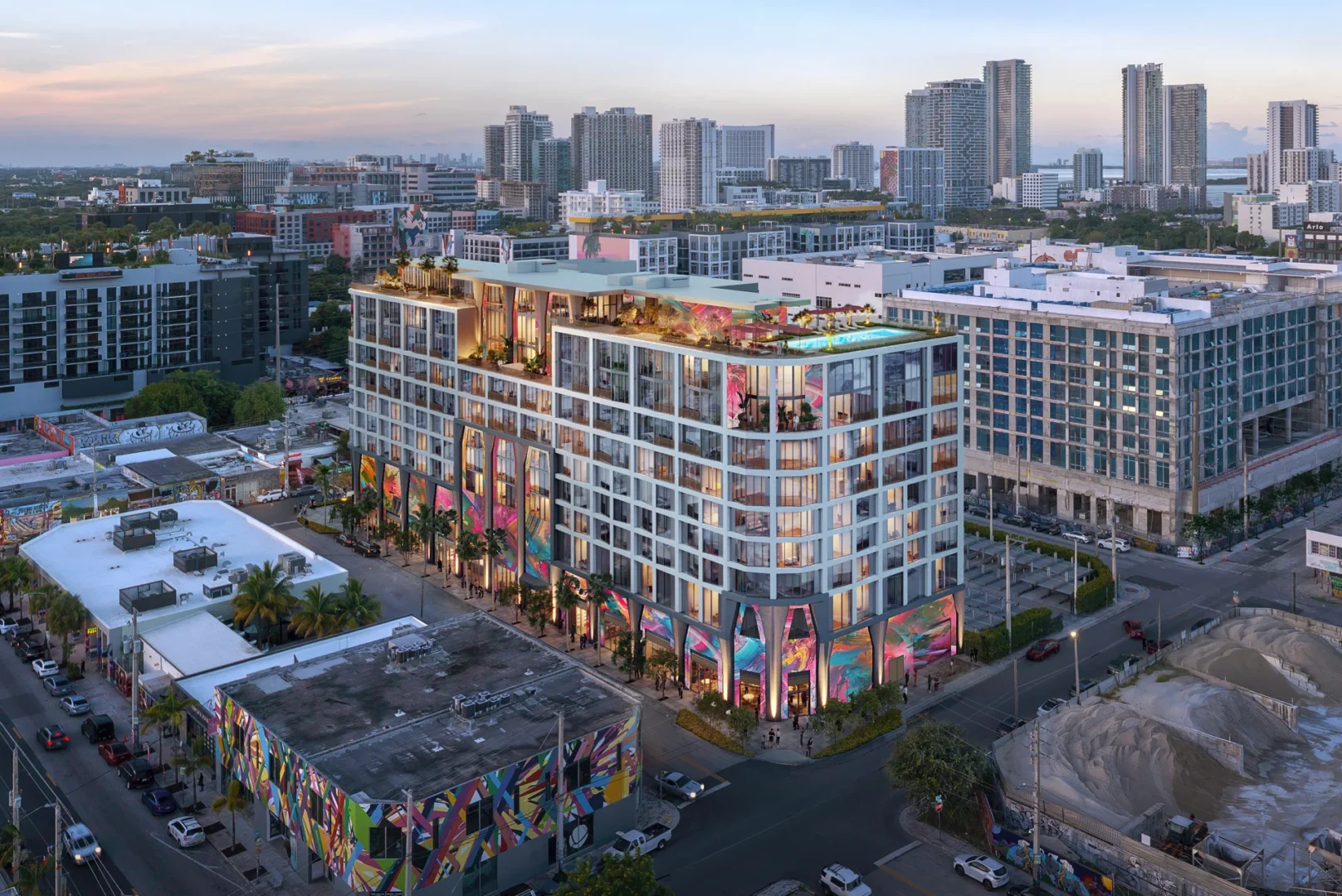 El Cloud One Hotel & Residences Wynwood, un edificio de varias plantas con coloridos murales y una terraza en la azotea, destaca en el perfil urbano de la ciudad.
