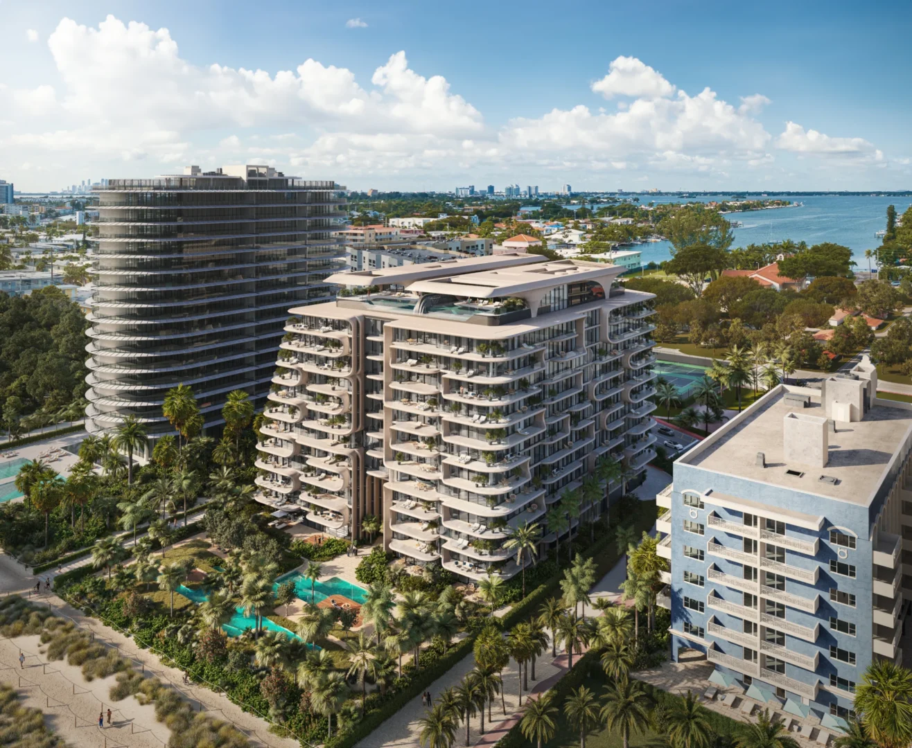 Multi-story buildings in The Delmore feature balconies near palm trees, swimming pools, and water with people visible on paths