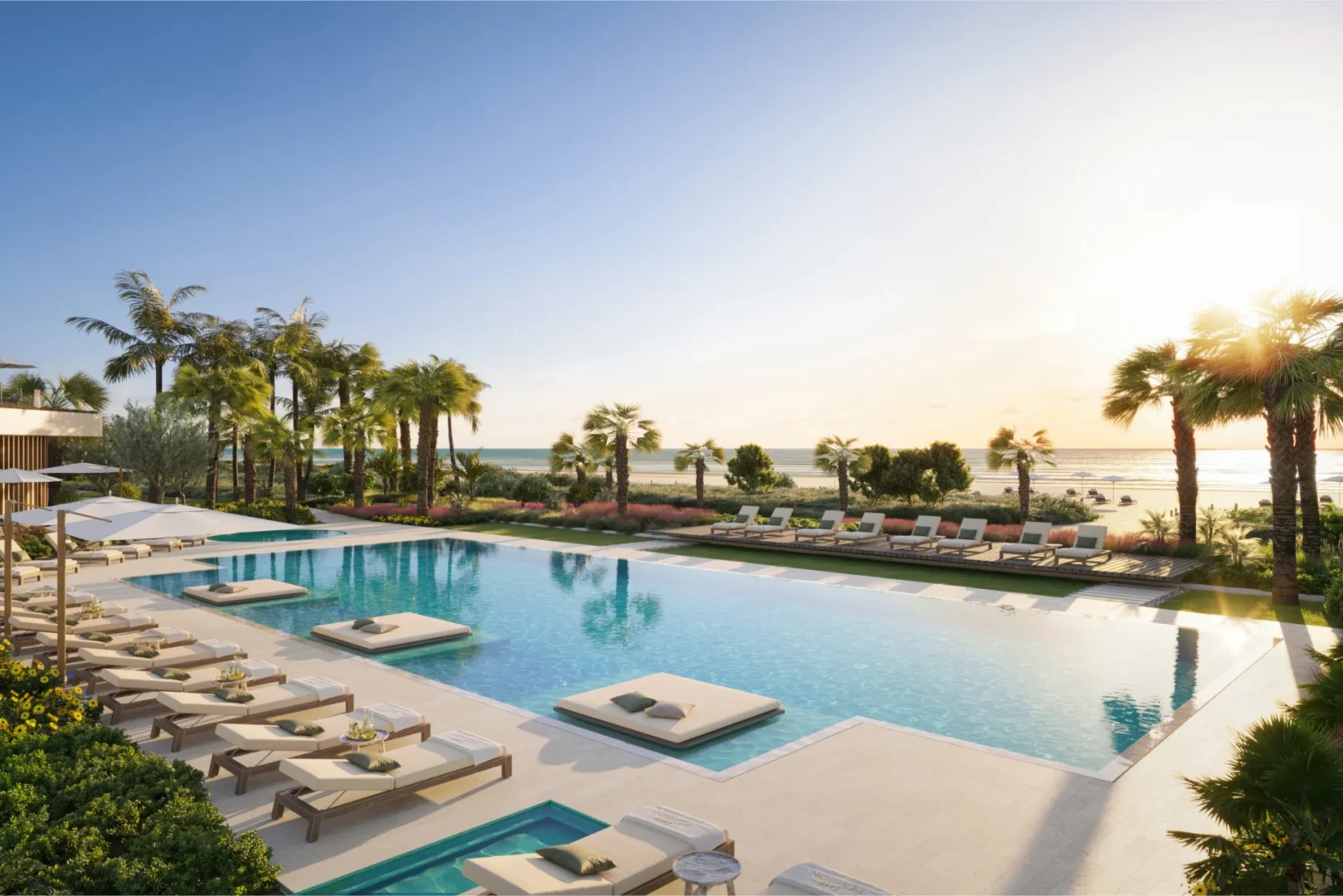 A large swimming pool with lounge chairs and palm trees is at The Perigon near the sea