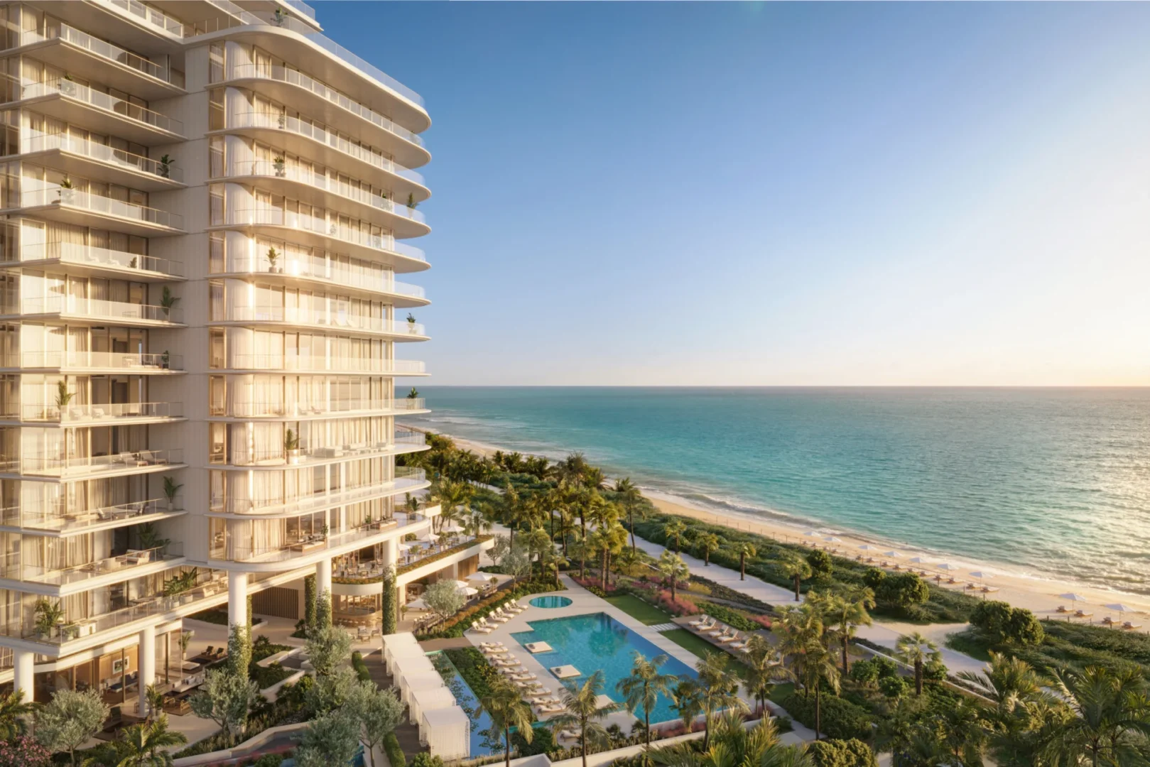 A multi-story building with balconies at The Perigon overlooks a swimming pool, palm trees, and the ocean