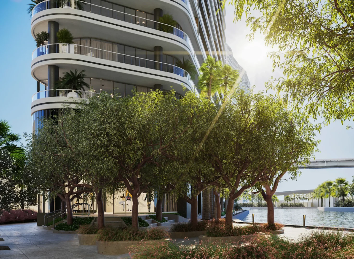 Curved balconies and glass windows of Two Riverside rise above trees beside water