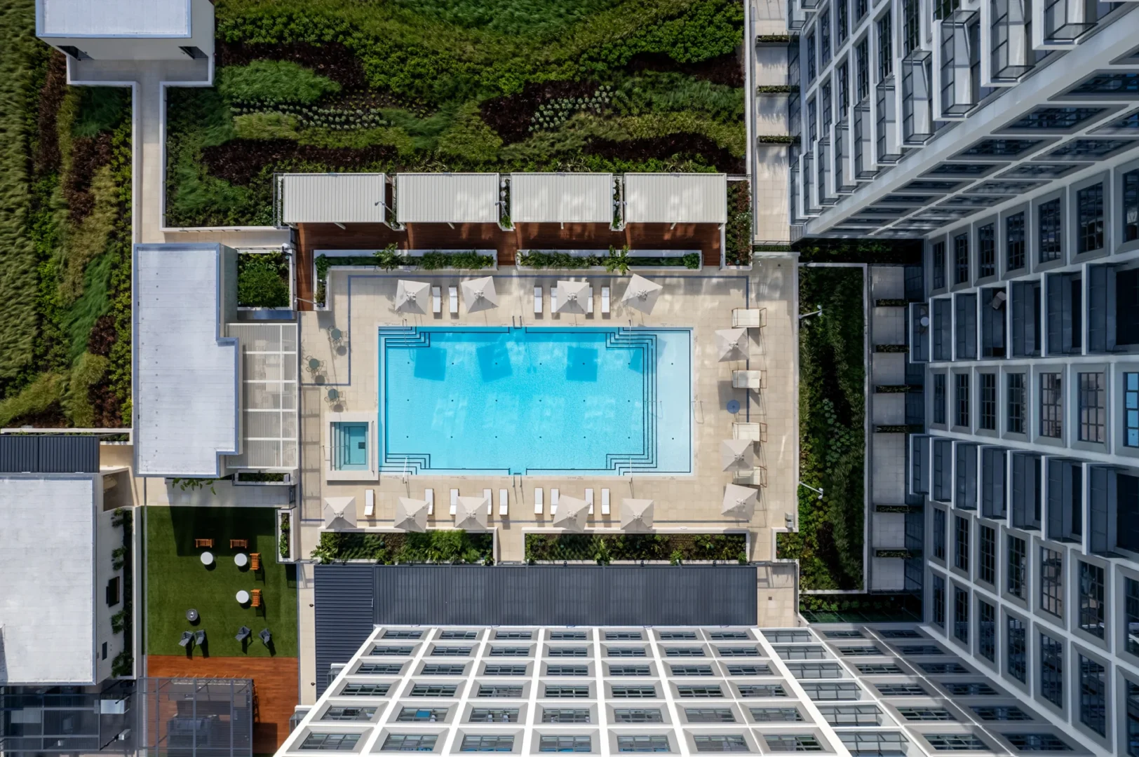 La piscina azul y la terraza ajardinada del Asher Water Street Tampa están rodeadas de edificios modernos