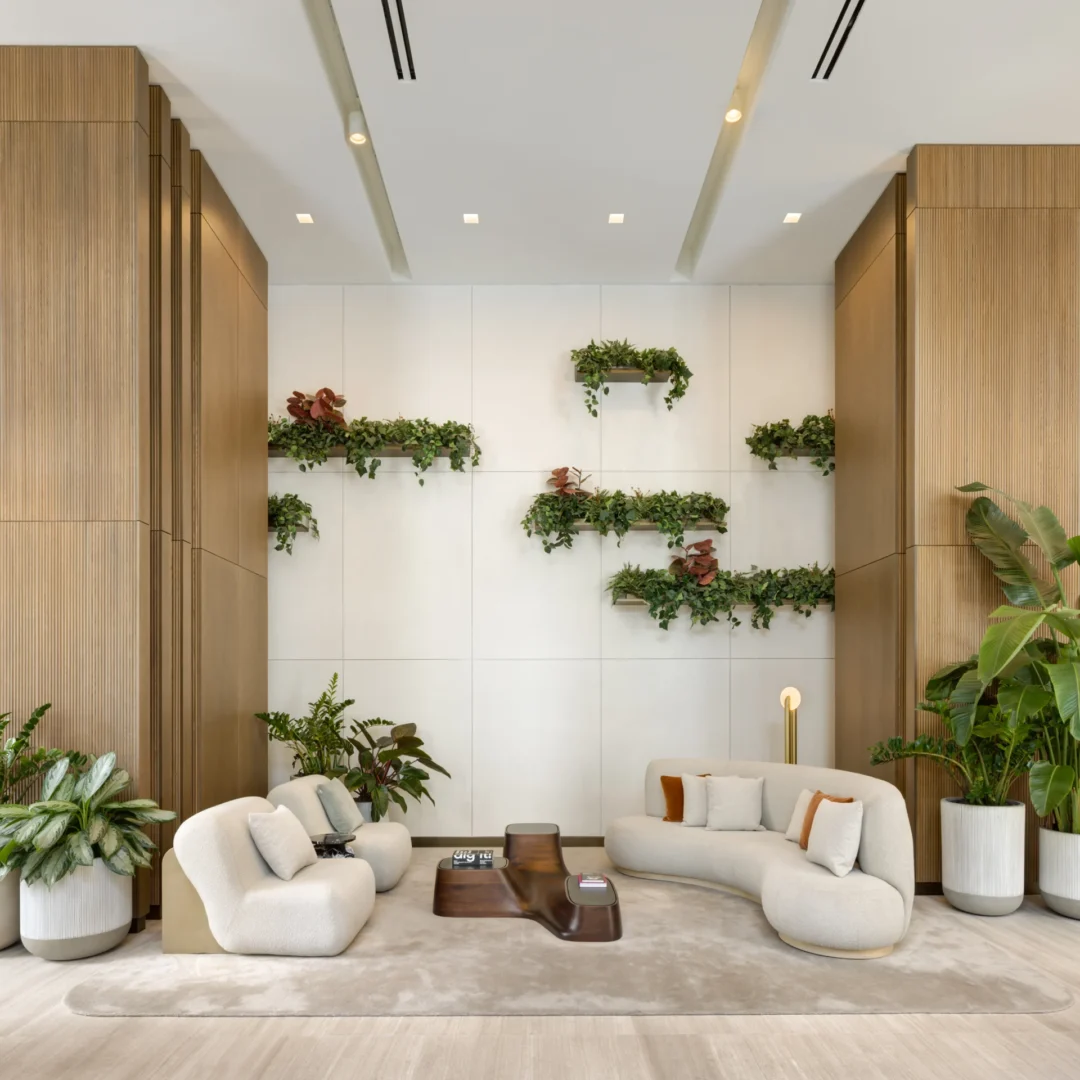 A lounge in the Forma project features white curved furniture, wood-paneled walls, and floating plant shelves