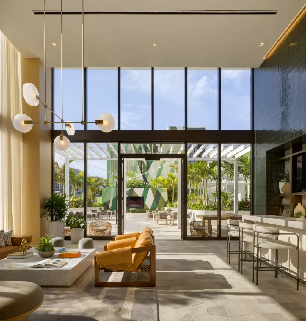 Large floor-to-ceiling windows in the Forma lounge overlook an outdoor terrace with greenery and seating
