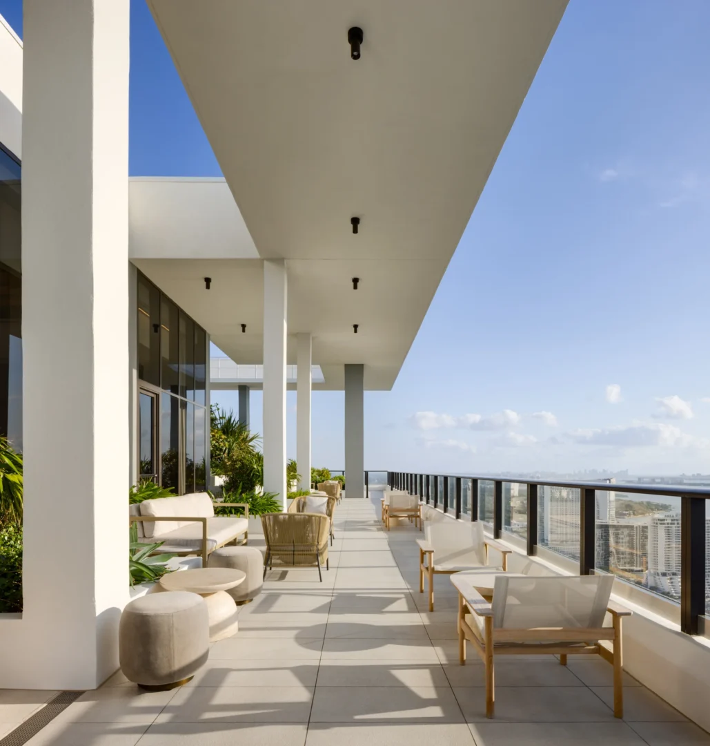 White architectural pillars and an overhang shade a terrace with seating in the Forma project overlooking a distant view