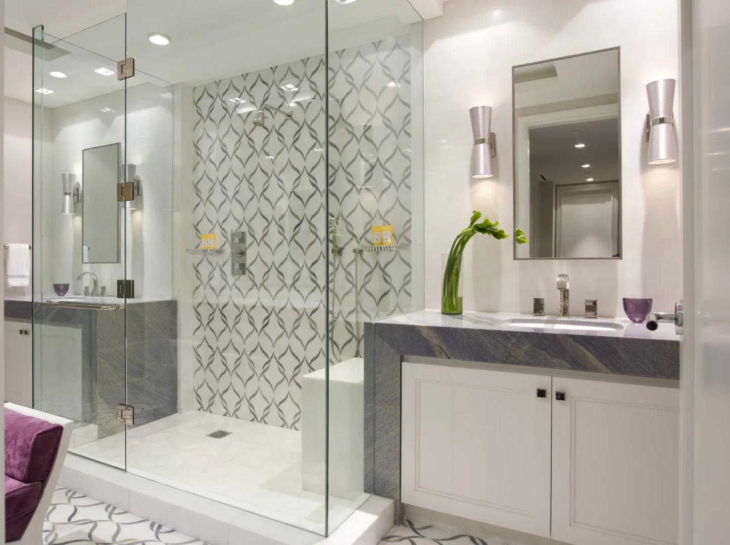A glass shower enclosure with patterned tiling stands beside a stone-topped vanity in the Penthouse 4 bathroom