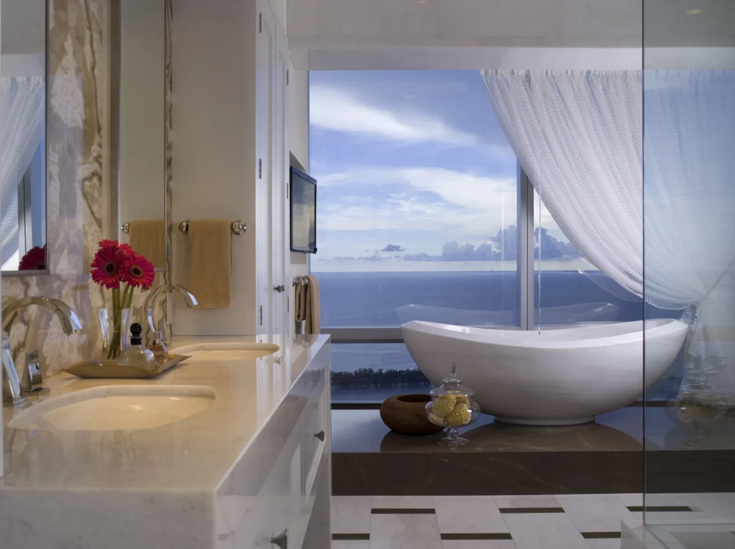 A white freestanding bathtub sits by a large window with an ocean view in Penthouse 4