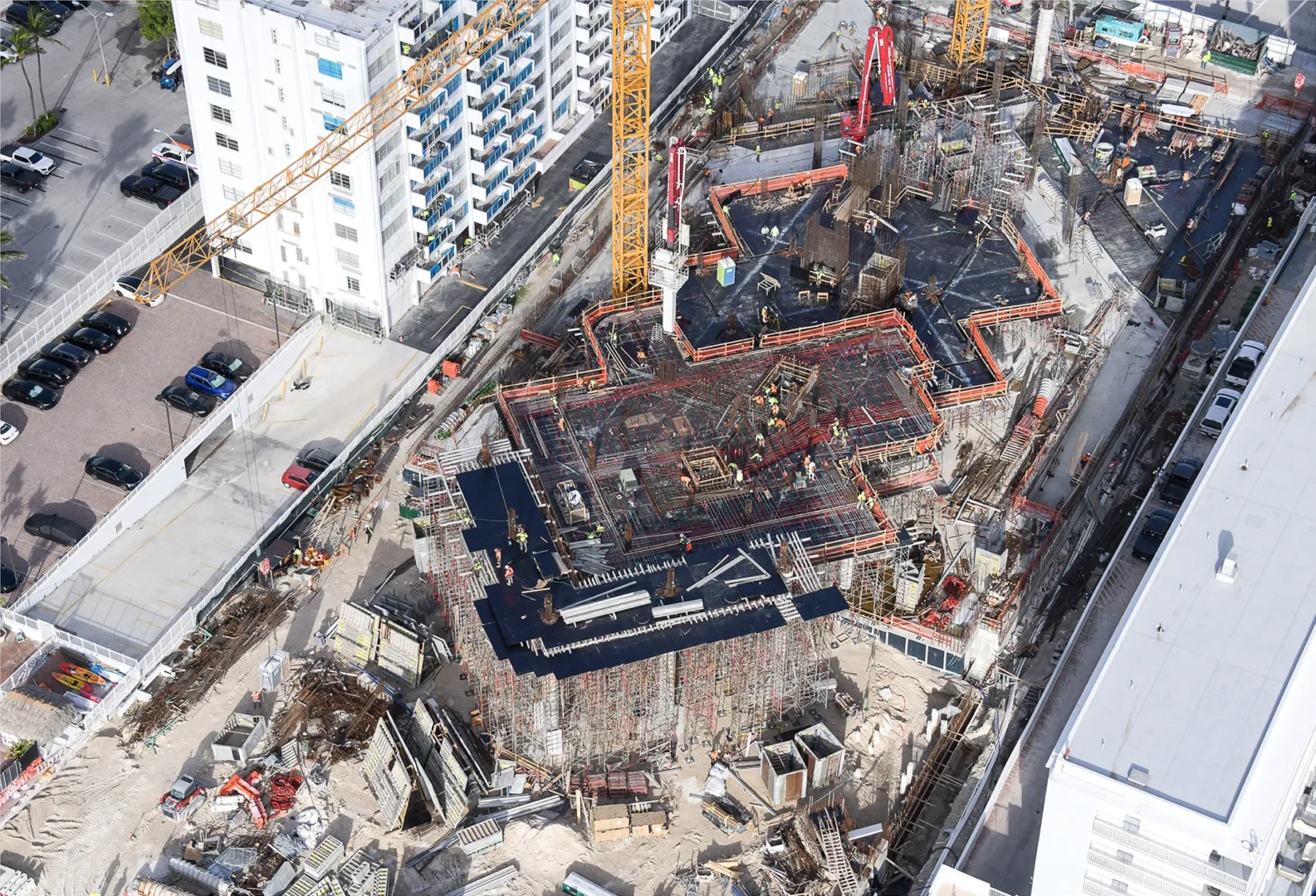 Construction cranes and workers are visible on the active building site of The Perigon among surrounding urban structures