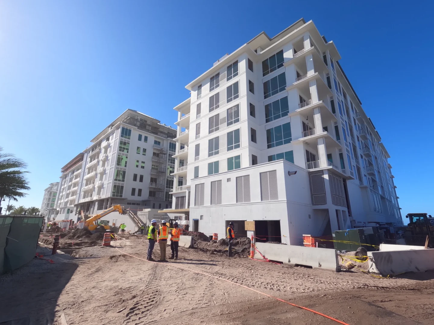 En los grandes edificios blancos del Four Seasons Resort & Residences de Naples Beach se ven obreros de la construcción y una excavadora sobre tierra