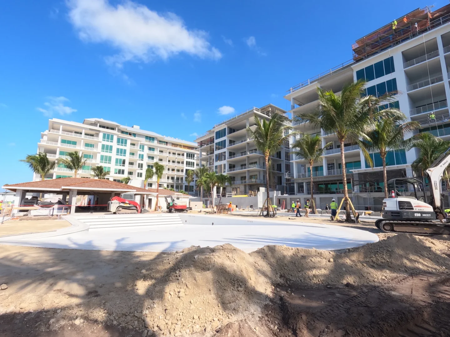 Los edificios de varias plantas en construcción en el Four Seasons Resort & Residences de Naples Beach incluyen palmeras, una excavadora y trabajadores.