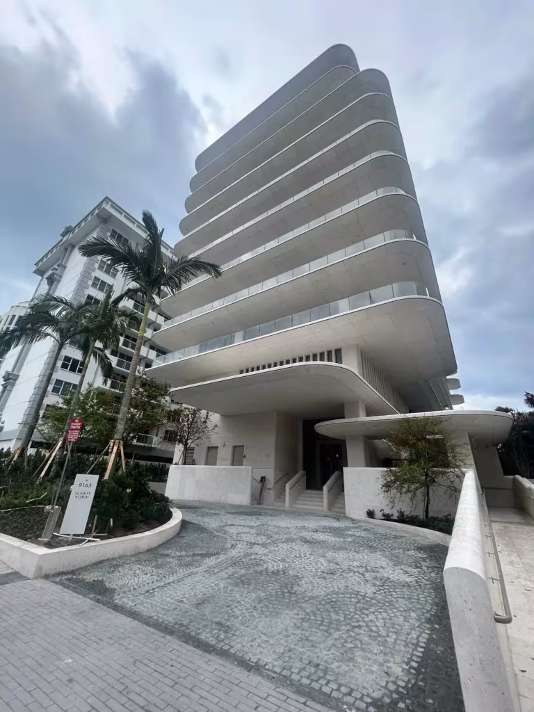 En Hillcrest, un edificio blanco de varias plantas con balcones redondeados se alza detrás de unas palmeras bajo un cielo nublado