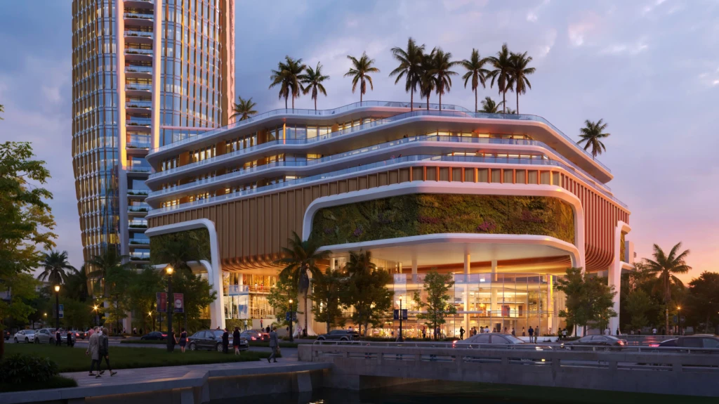 Un edificio de varias plantas del proyecto «Isles Of Dreams» cuenta con terrazas en la azotea, palmeras, fachadas acristaladas a pie de calle y gente paseando.